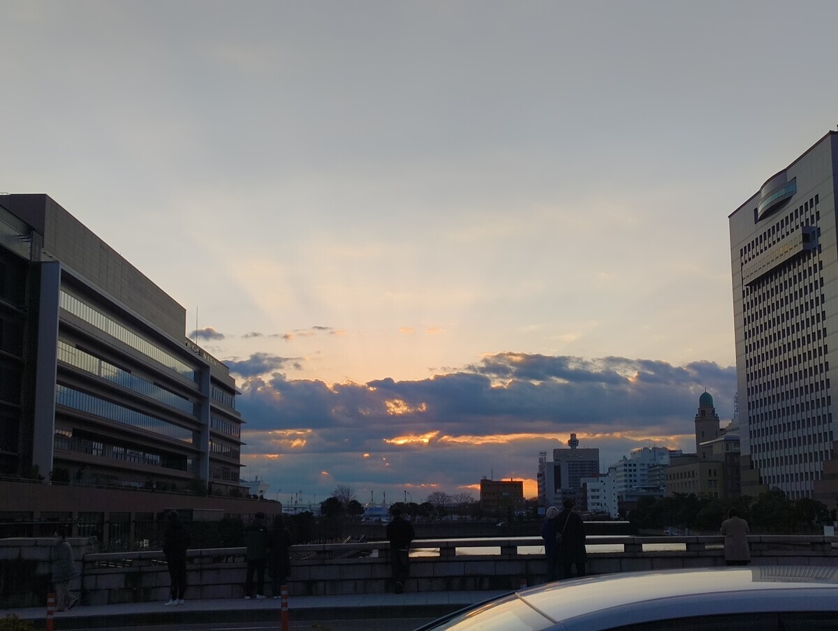 横浜の万国橋から空を臨む写真。初日の出を臨むが、雲に阻まれた向こうからわずかに日光が漏れでるのみで太陽は見えない。