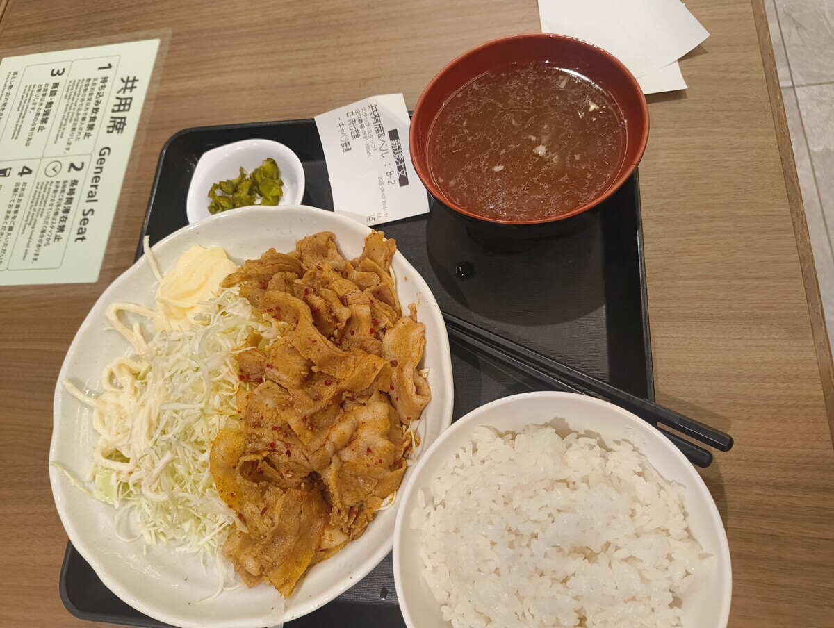 七味で炒めた豚肉と千切りキャベツが乗った皿、スープ、ごはんの写真。