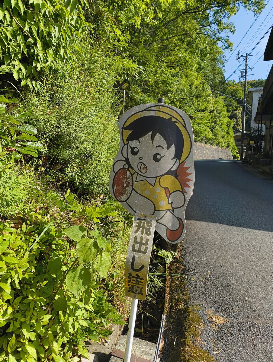 飛出し注意、と書かれた児童向けの古びた標識が、街角に置かれている写真