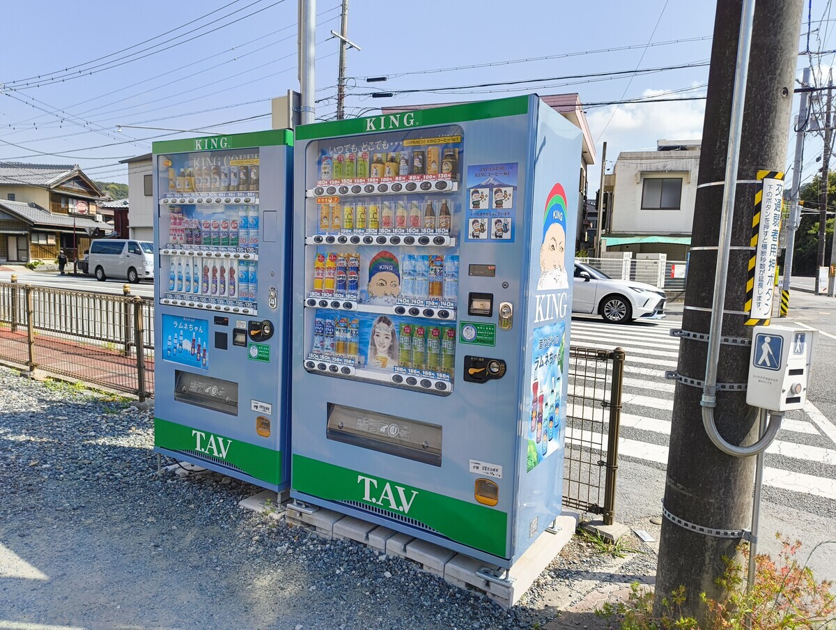 キングコーヒーの自動販売機が2つ並んだ写真。水色の筐体で、側面には「KING」と書かれたカラフルなニット帽をかぶった、白いあご髭の老人の顔が描かれている