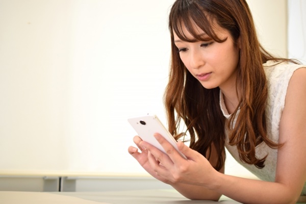 病院でスマホゲームをする女性