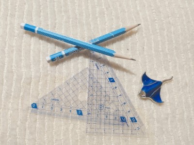 白い背景に鉛筆2本と三角定規とマンタのキーホルダー