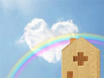 木製の病院のミニチュアとハートの雲と虹