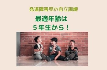 レンガの壁の前でアイスクリームを持って床に座る３人の男の子