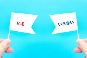 水色の背景に「いる」「いらない」と書いた旗を持つ指