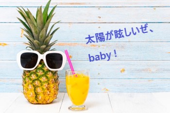 白い背景にサングラスをしたパイナップルとパインジュース