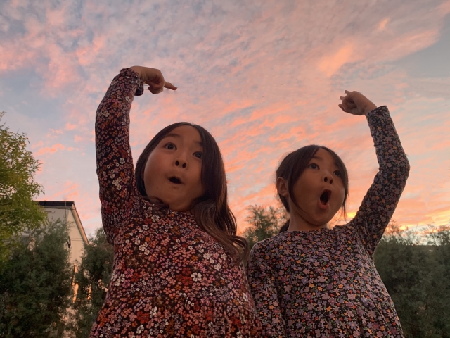 夕焼けにガッツポーズをする女の子