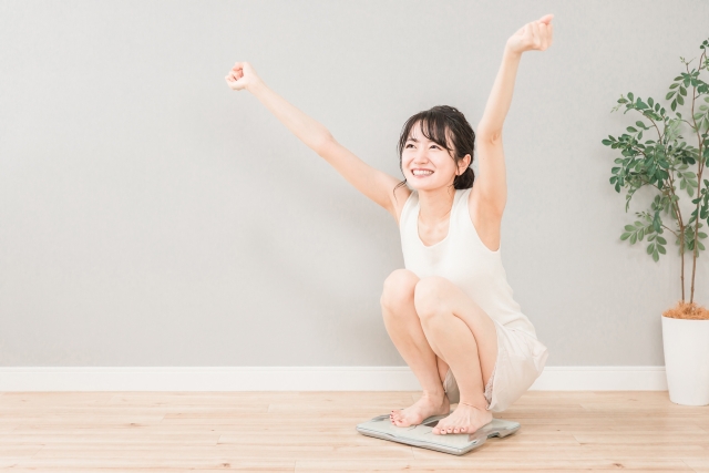 体重計の上で万歳をする女性