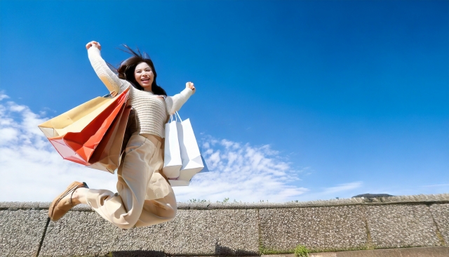 ショッピングバッグを手にジャンプする女性