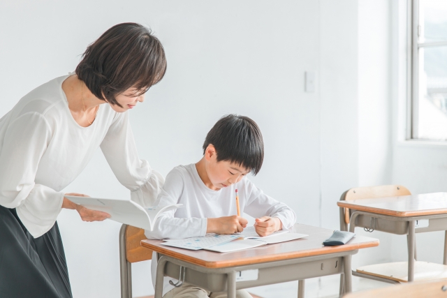 字を書く男の子と先生
