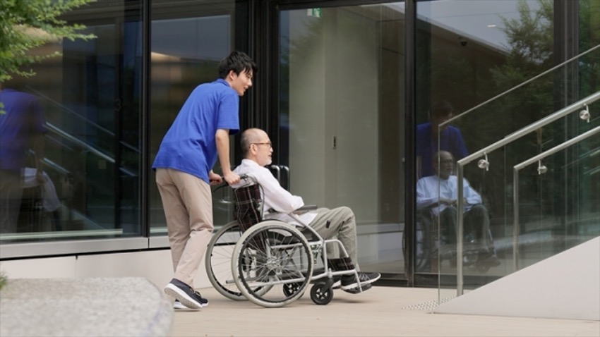 高齢者が乗車する車椅子を押す男性介護士