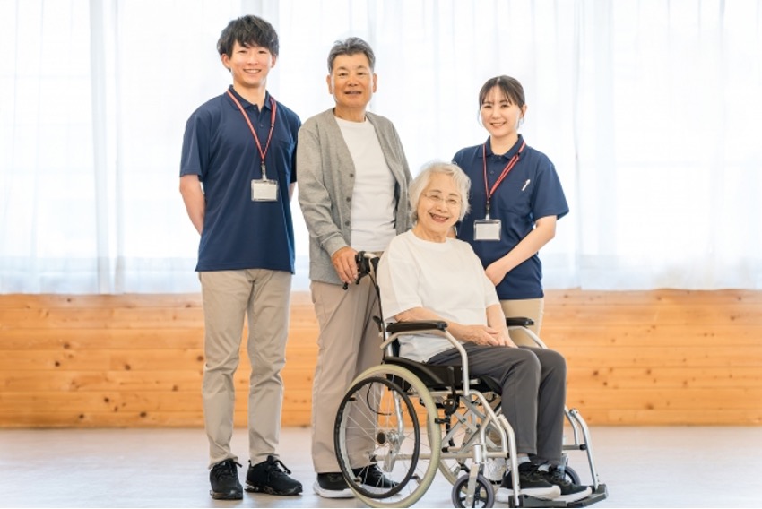 車椅子に乗った高齢者女性を囲む家族と介護士