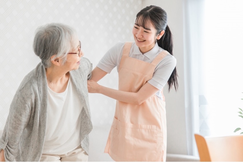立ち上がる高齢者女性の腕を支える介護士