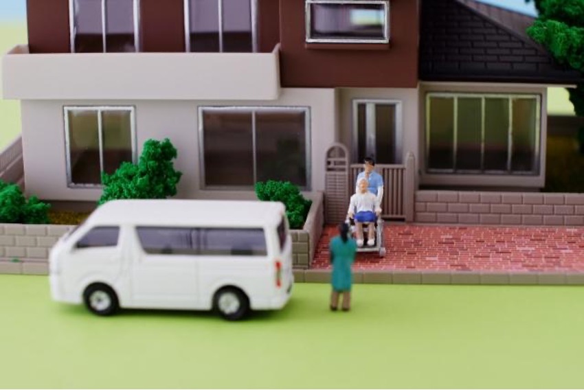車いすの男性を乗車させる介護スタッフ