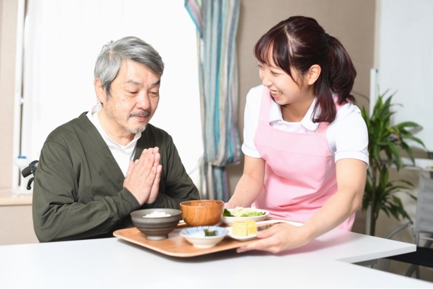 高齢者に食事の配膳をする介護士