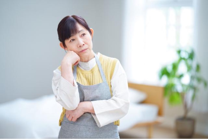 寝室で悩む中年女性 