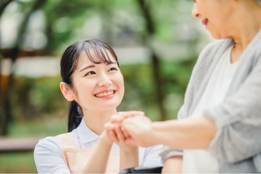 車椅子に乗った高齢者の手を握る介護士