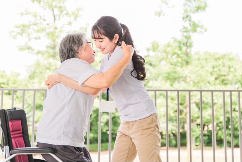 高齢女性の移乗・移動介助をする女性介護士