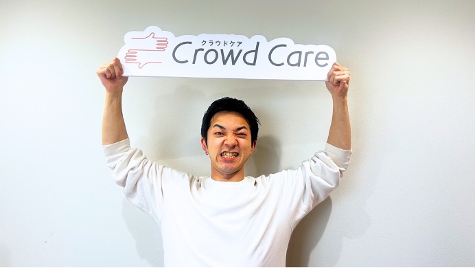クラウドケアの看板を掲げる男性介護ヘルパー