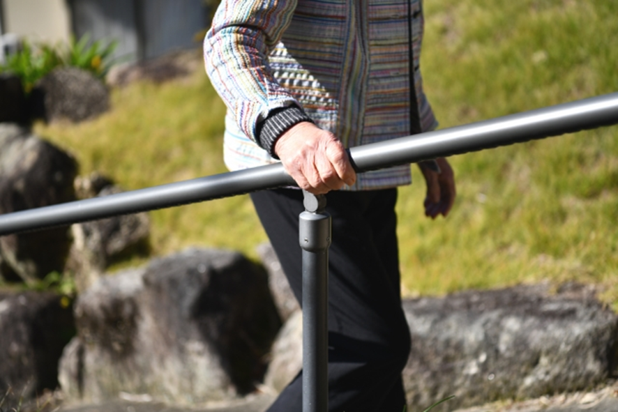 手すりを持ち、階段を上る高齢者