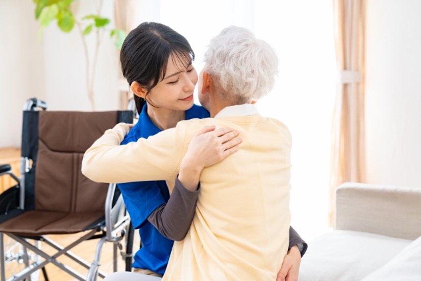 高齢女性を優しく抱きかかえる女性介護スタッフ