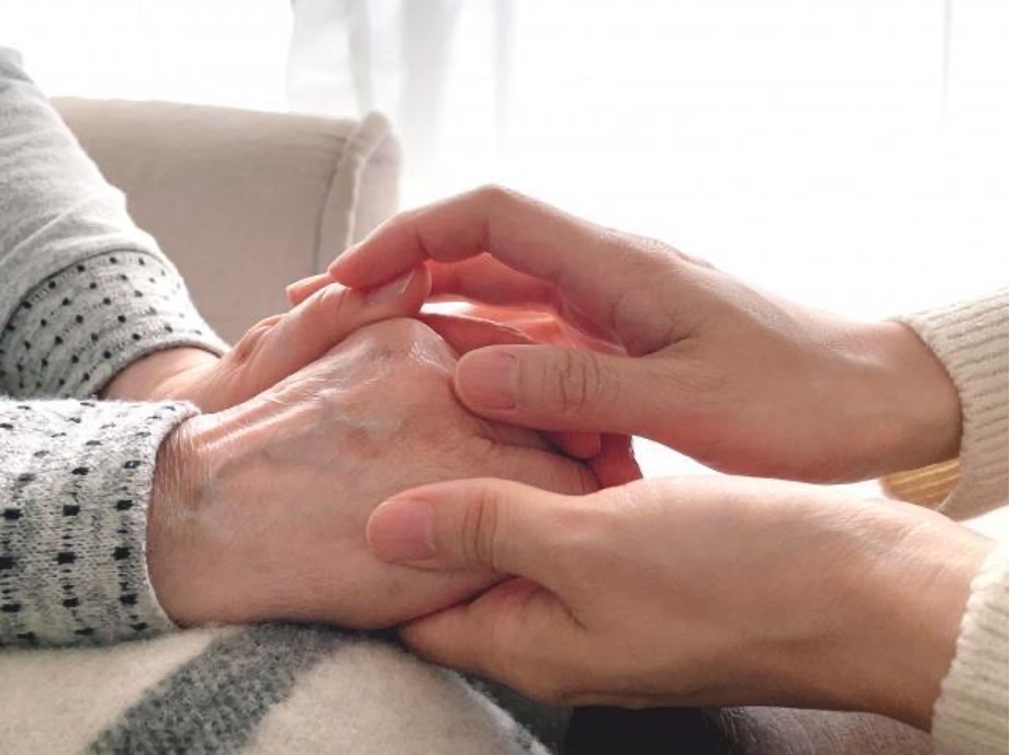 高齢者の手と上と下からそっと優しく包み込む若者の手
