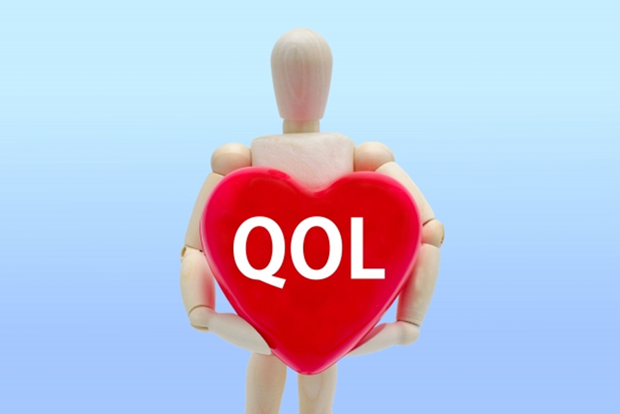 QOLと書かれたハートを持つ人形