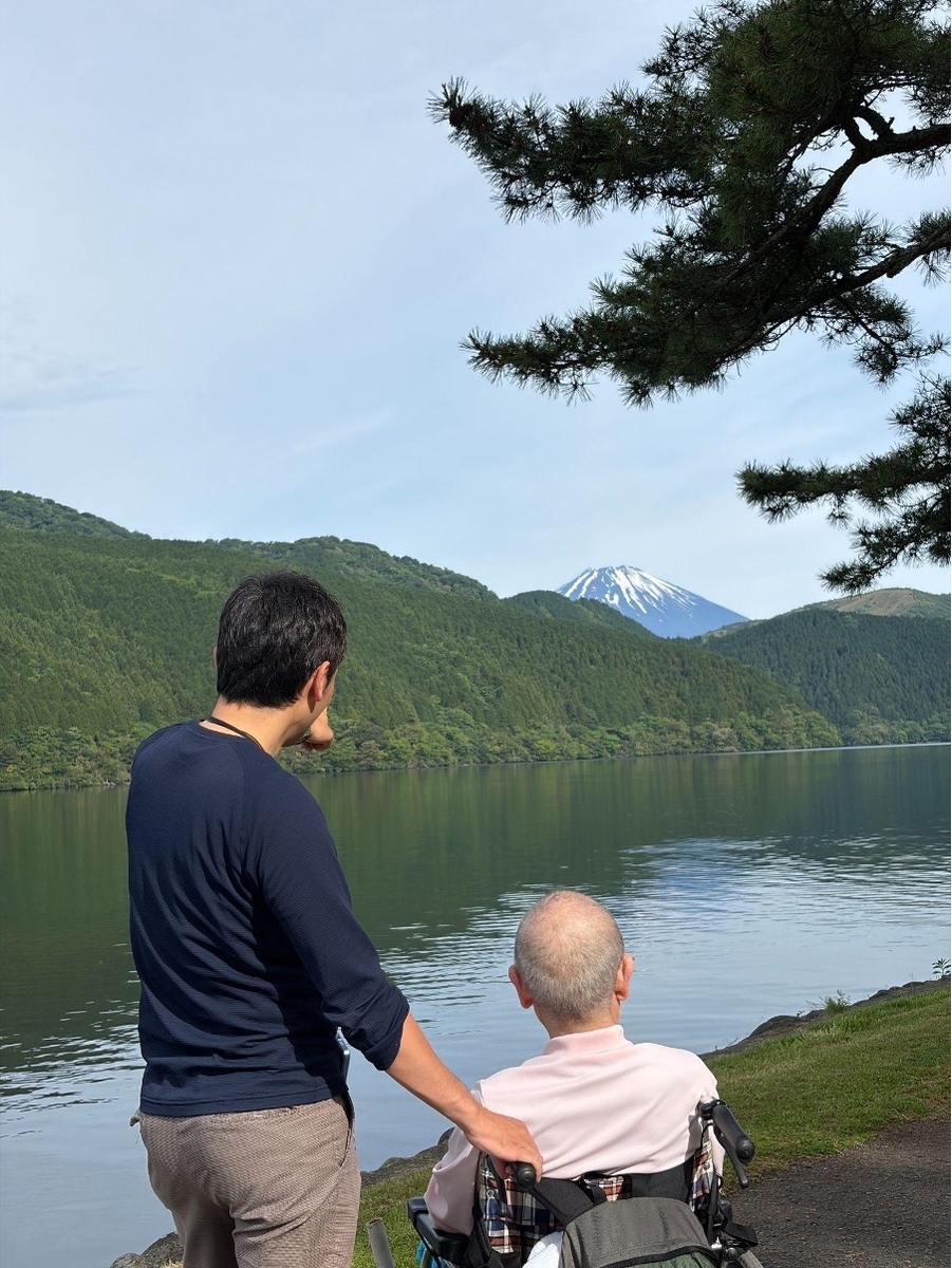 湖畔にいる車椅子男性と介助をする男性