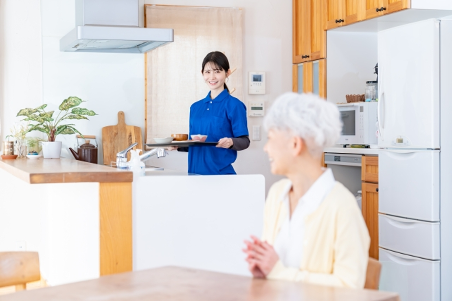 高齢女性に食事の用意をする介護士