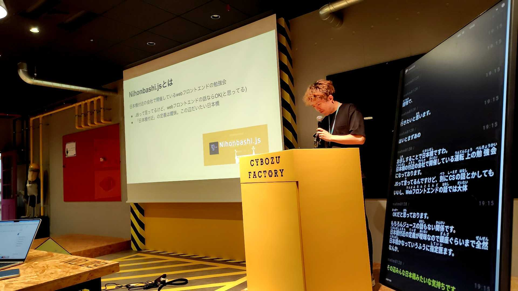 Nihonbashi.jsについての説明をしているSajiさん。右側にUDトークが表示されているディスプレイが見えている。