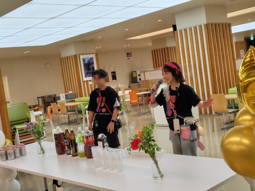 懇親会でアナウンス中のsakuさん。隣には別の運営メンバーが立っている