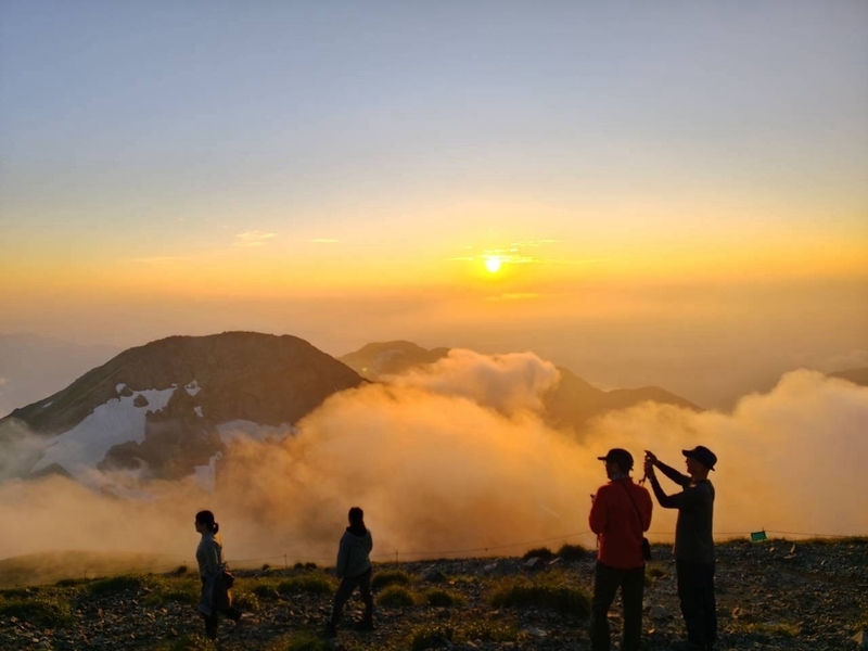 白馬岳山頂から見た夕日と、オレンジに染まる雲海と登山者たち