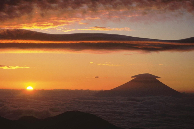 日の出の富士山の山頂にレンズ状の雲がかぶさり、左手の空にも小さなレンズ状の雲が浮いている