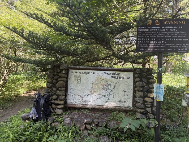 羽衣池入口の手前に立つ八ヶ岳横断歩道案内図と、無計画な入山を戒める山梨県の警告看板
