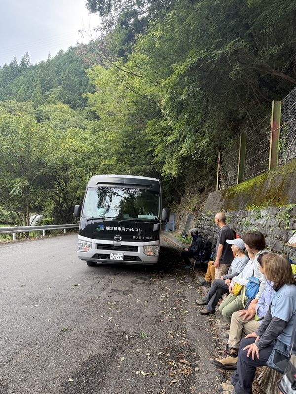畑薙の林道脇に停まった特種東海フォレストの送迎バスと、乗車を待つ登山者たち