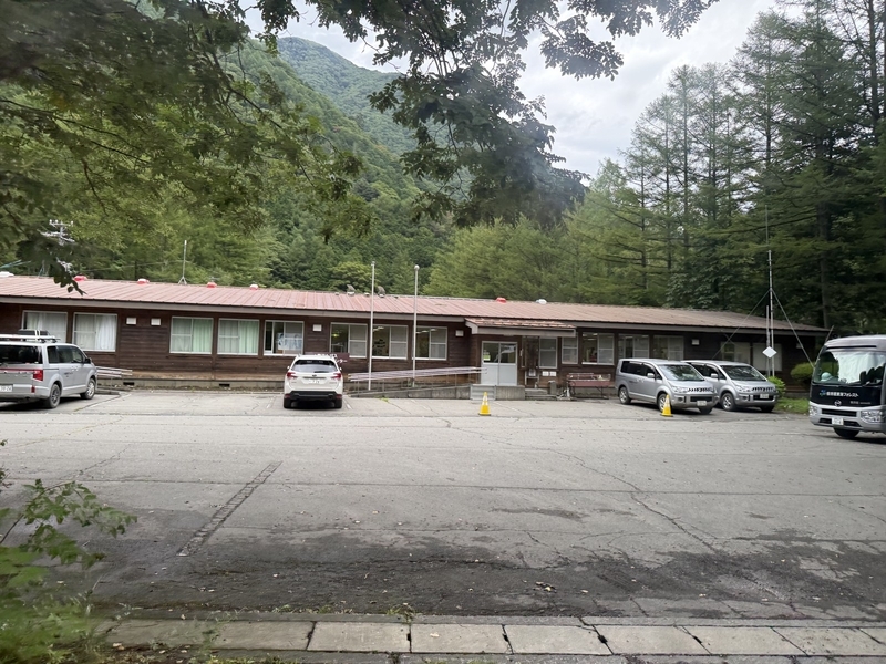 椹島ロッヂの木造の建物と駐車場