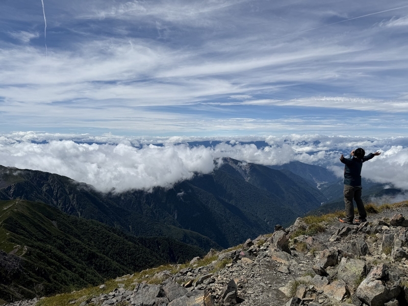 雲海を見下ろす稜線に立つ登山者のシルエット