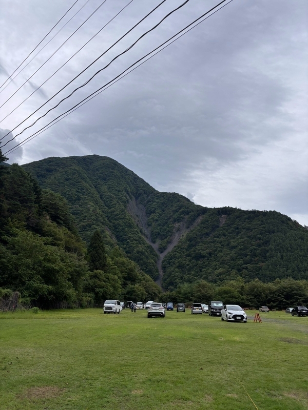 畑薙の駐車場の芝生で、ザックを広げて荷造りをする登山者たち