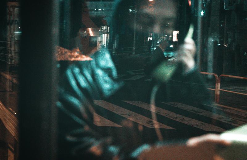 ガラスに映る公衆電話で話をする男