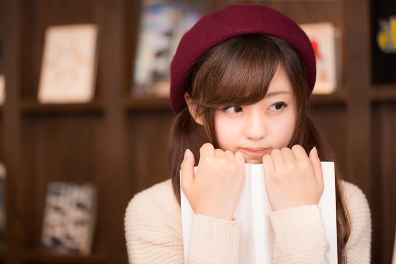 ベレー帽をかぶった若い女性が開いた本を抱きかかえている