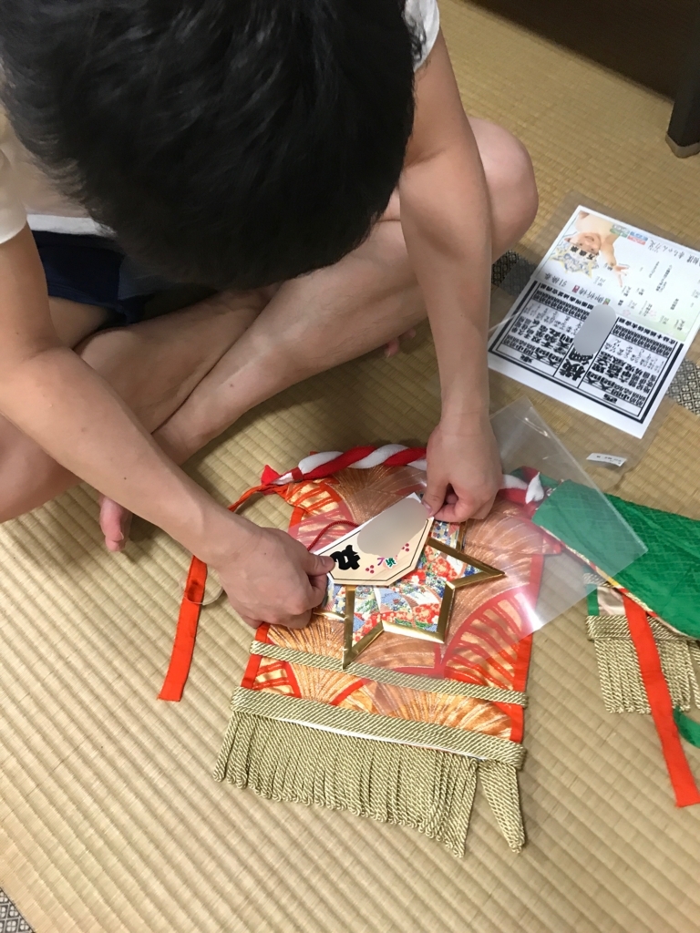 かぶとの真ん中に四股名のついたシールをはります