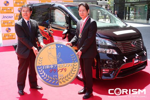 自動車アセスメントグランプリ表彰式でグランプリのメダルを授与する独立行政法人・自動車事故対策機構(NASVA・ナスバ)の金澤 悟 理事長と、「トヨタ ヴェルファイア/アルファード」開発責任者のトヨタ自動車 トヨタ第1乗用車センター 中越 祐三 チーフエンジニア