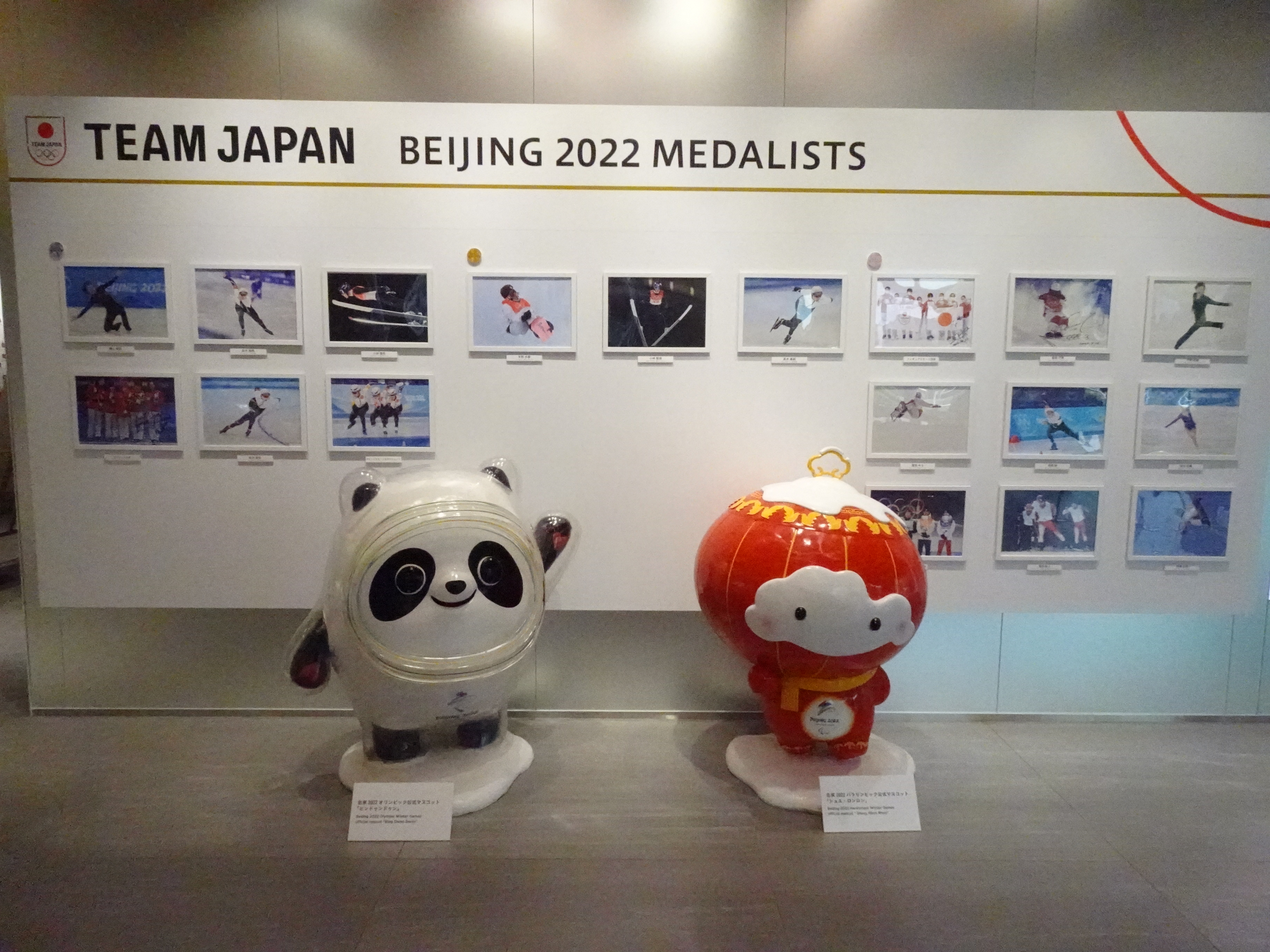 2022年北京冬季オリンピック日本代表選手団の金銀銅メダリスト一覧の前に、ビンドゥンドゥンとシュエ・ロンロンの人形が立っている