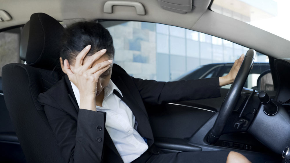 運転席で頭を抱える男性