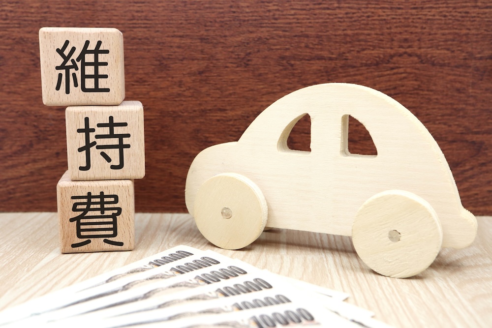 車の置物の隣に積み上げられた維持費書かれた積み木