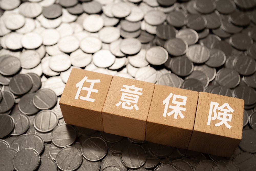 コインの上に置かれた任意保険の文字が書かれた積み木