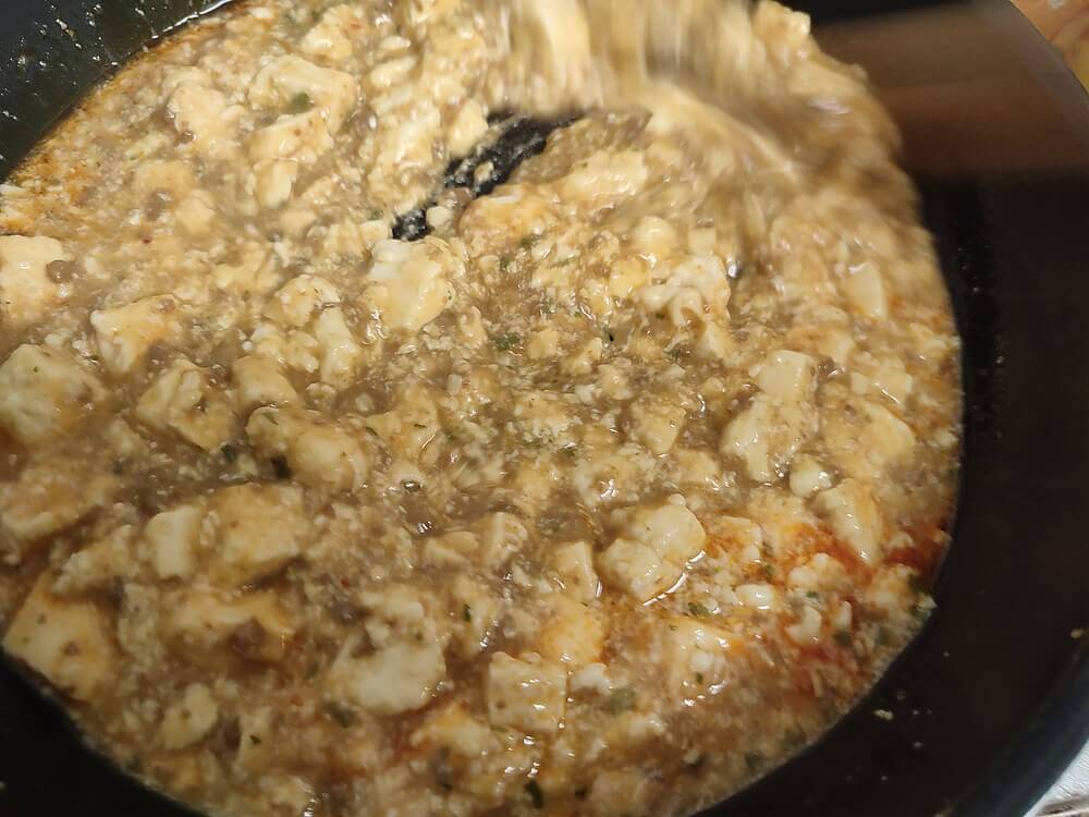 麻婆豆腐を菜箸で勢いよくかき混ぜる