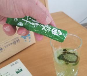 藍の青汁粉末をコップに注ぐ