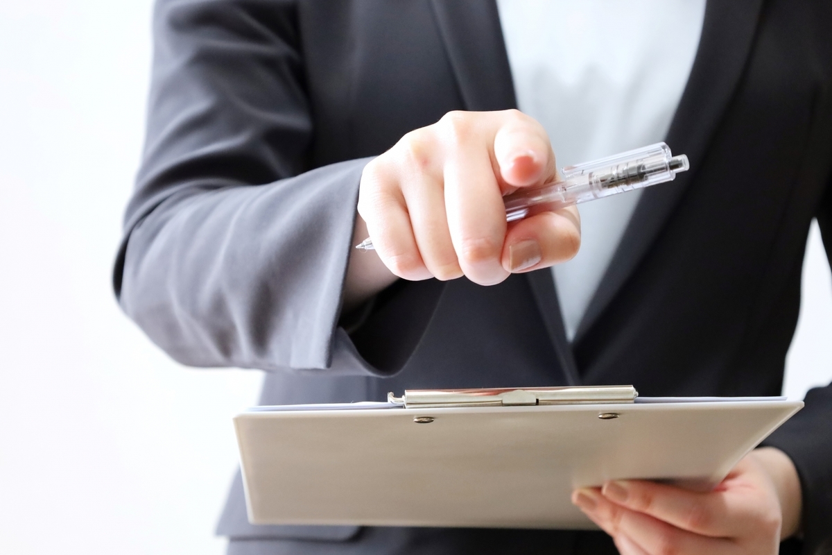 バインダーを持ち指をさす女性