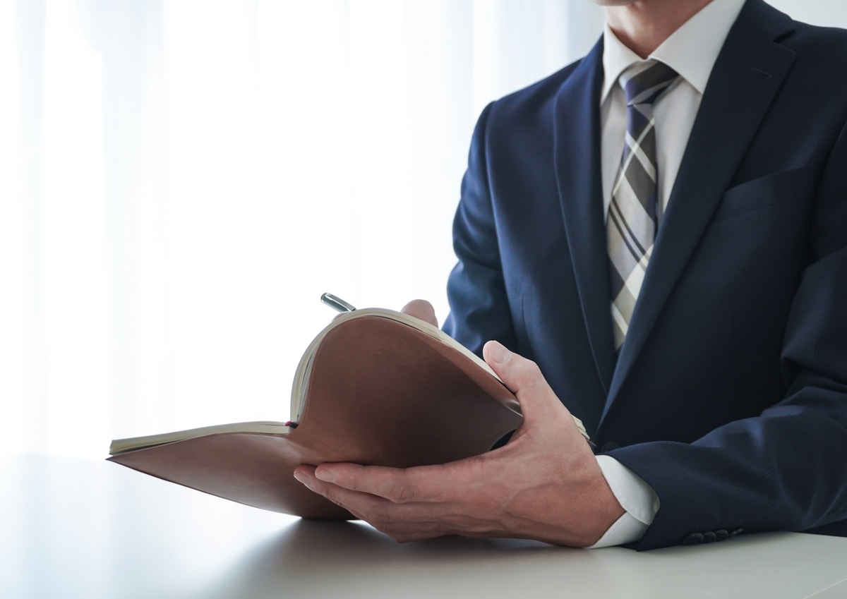 手帳に記入するスーツの男性